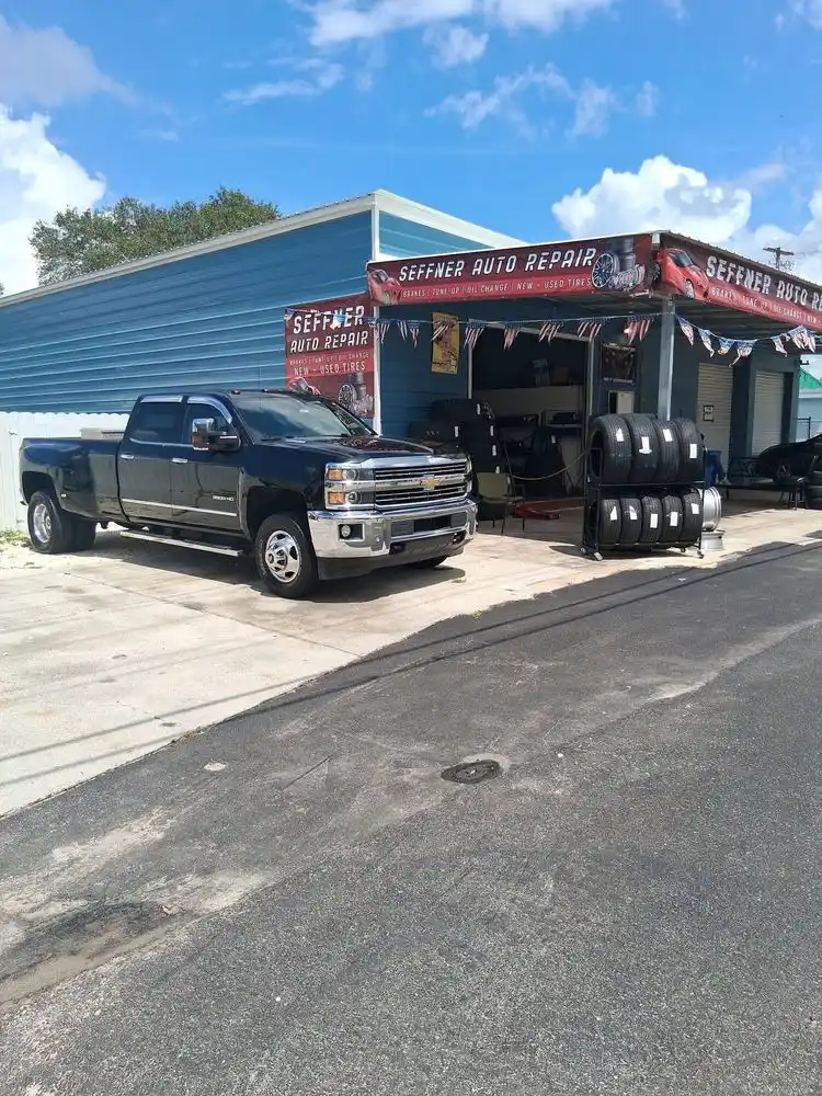 Black dually pickup truck parked in front of the Seffner Auto Repair tire bays