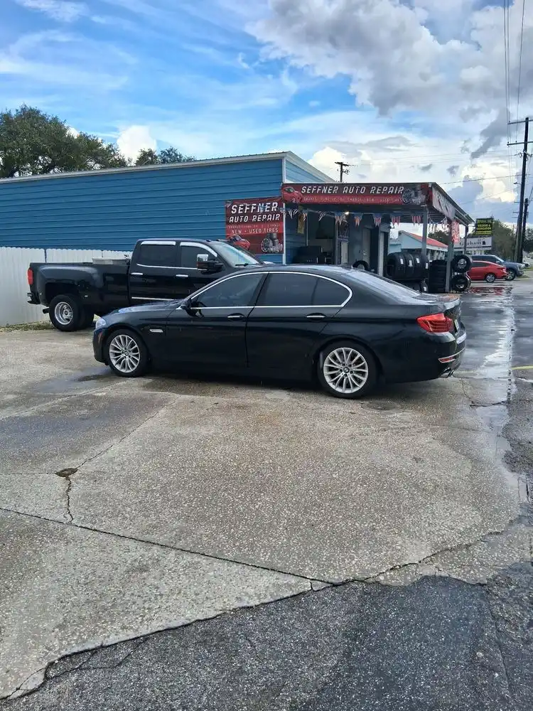 Black sedan and pickup truck parked outside Seffner Auto Repair after a rain shower