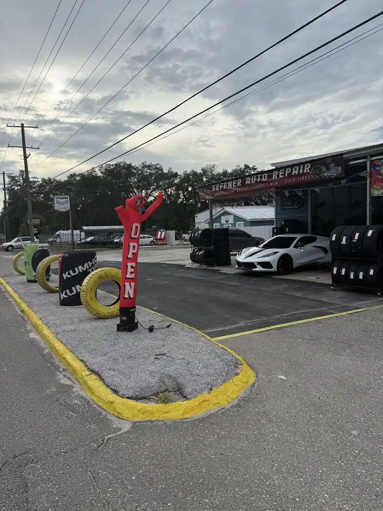 Inflatable open sign and painted tires along the curb in front of Seffner Auto Repair