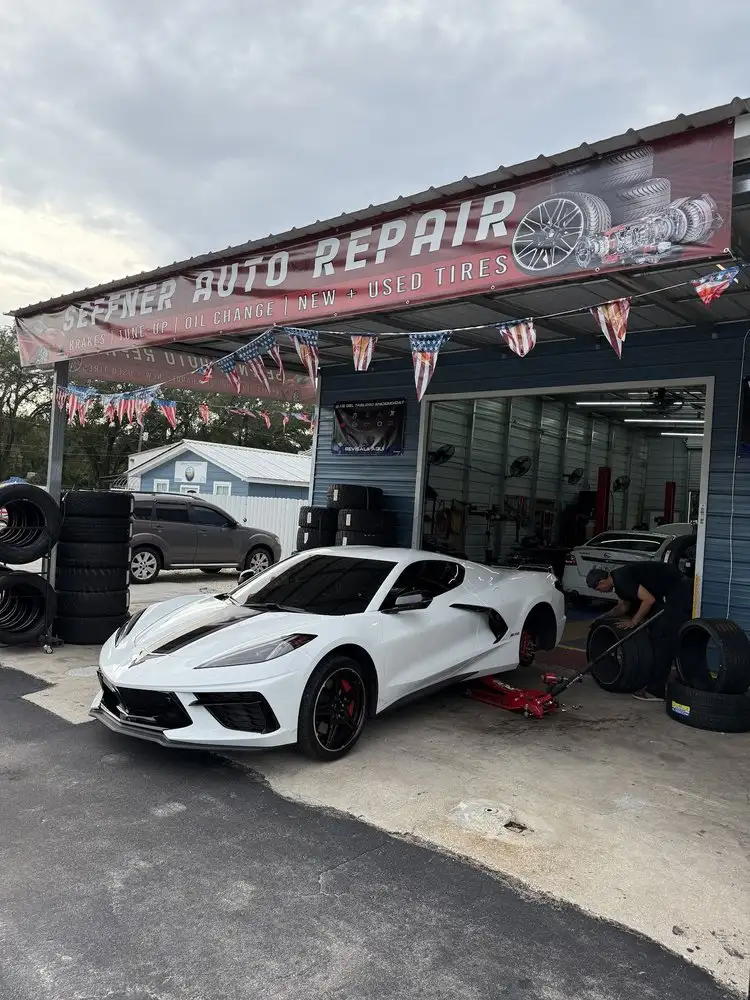 White Corvette at the Seffner Auto Repair bay while tires are changed beside it